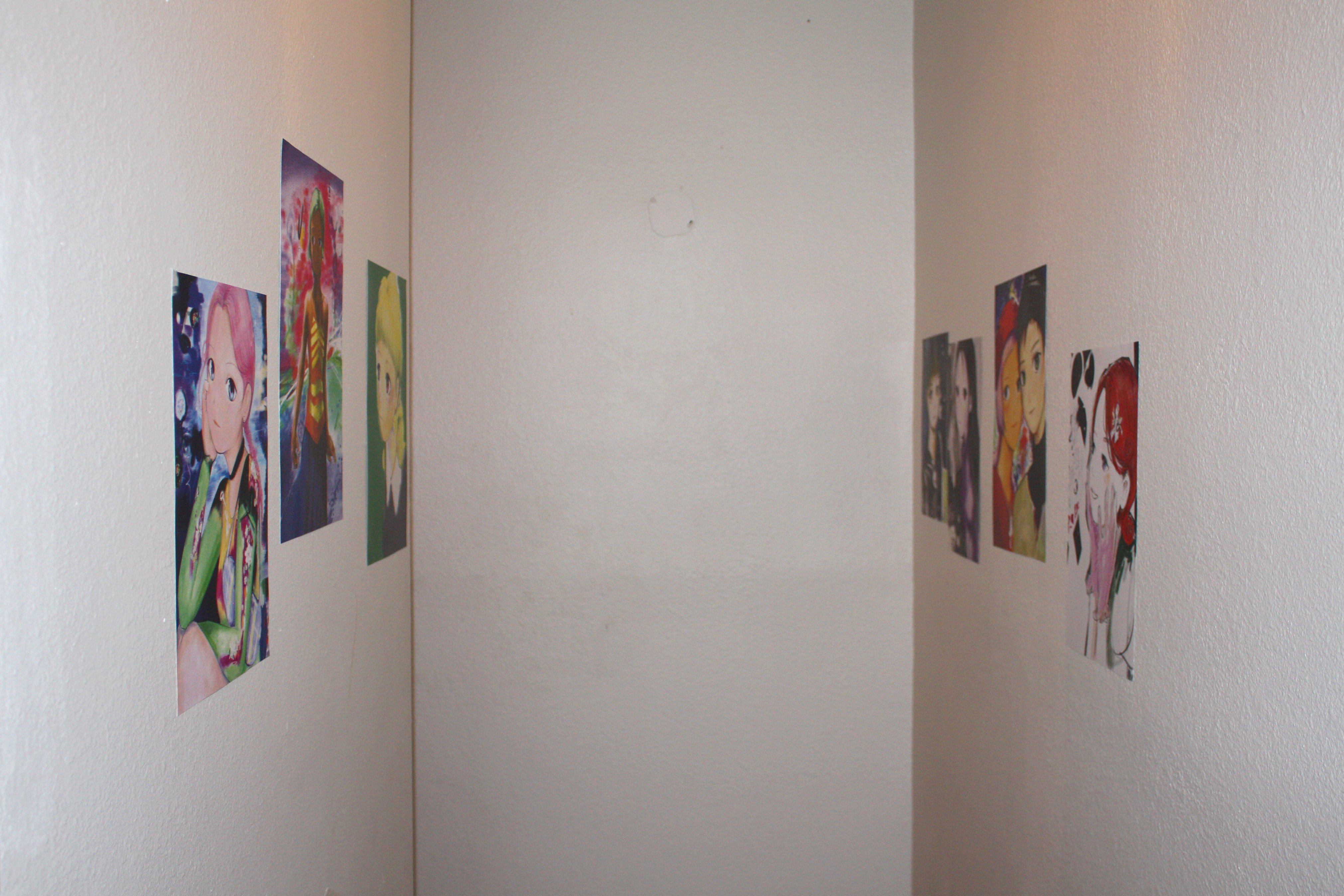 Six prints hung in a narrow white hallway